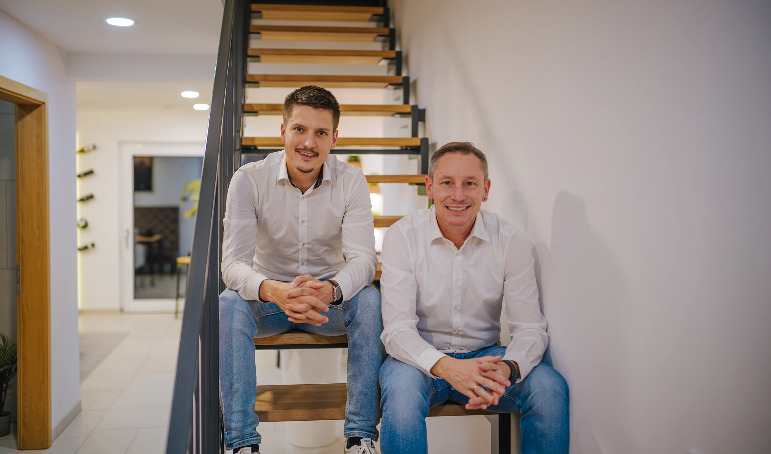 Michael Zeiehr und Nicolaj Pietsch sitzen auf einer Treppe.